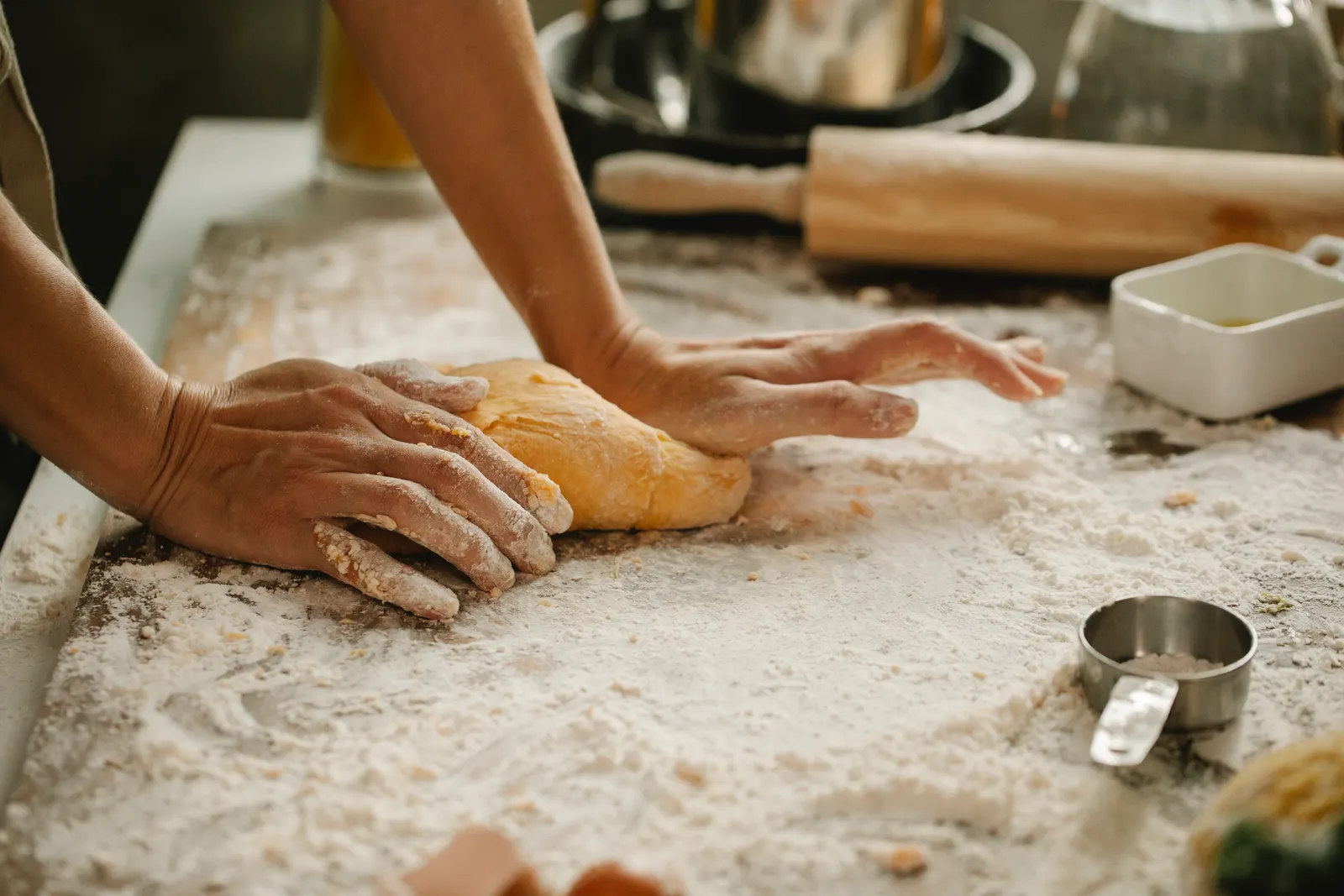Hands kneading dough on a floured table